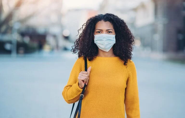Mulher negra de máscara em lugar vazio durante a pandemia: distanciamento social