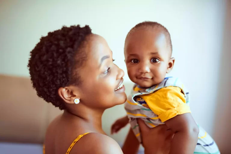 Foto de uma mulher sorrindo segurando um bebê feliz